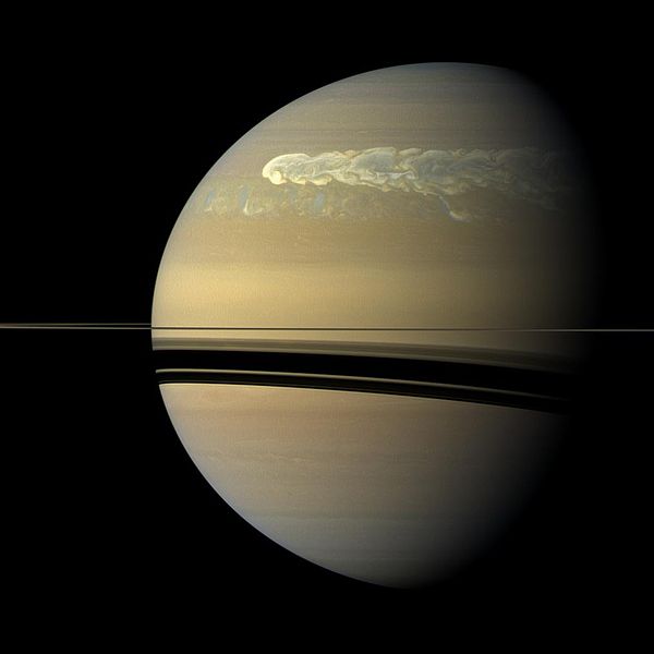 Der Planet Saturn: In der oberen Hälfte der Atmosphäre eine helle, wirbelige Schliere, die sich um den Planeten zieht.